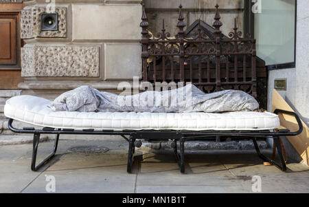 Una traversina ruvida del luogo di riposo per la notte nella forma di un campeggio Bed con materasso e coperta sul marciapiede sulla Piccadilly nel centro di Londra. Il fenomeno dei senzatetto è diventato un più visibile il problema ancora una volta a Londra negli ultimi mesi e ci sono stati tentativi controversi per rimuovere le traversine ruvida dalle strade sia a Londra e Windsor nelle settimane di funzionamento fino al Royal Wedding. Credito: Imageplotter News e sport/Alamy Live News Foto Stock