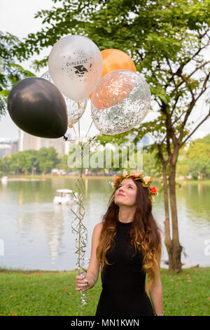 Giovane bella donna celebrando la laurea presso il parco in Bang Foto Stock