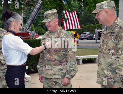 New York esercito Guardia Nazionale Maggiore Generale Steven Ferrari riceve il suo due stelle di rango dalla sua moglie Tracy come maggiore generale Raymond scudi, comandante della New York Army National Guard guarda su nel corso di cerimonie di Sabato, 12 agosto 2017 presso la Divisione Arcobaleno Memorial nella città giardino, N.Y. La Ferrari di promozione ha avuto luogo durante una cerimonia della divisione di centesimo anniversario. Garden City è stato il sito di Camp Mills nel 1917, dove la divisione formata. Nwe York membro divisione di militari e gli affari navali foto di Capt. Contrassegnare Getman. Foto Stock