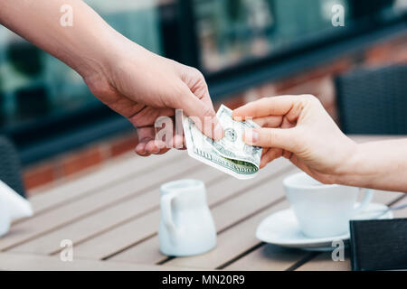 Pagando con dollari note in un cafe, close-up Foto Stock