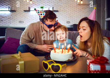 I genitori con una torta a congratularmi con il loro bambino per il suo compleanno. Foto Stock