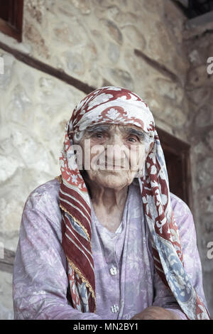 Unidentified vecchio turco donna musulmana pone per la fotocamera nella parte anteriore di una vecchia casa di pietra in Kemaliye,Erzincan,Turchia.Luglio 05 2014. Foto Stock