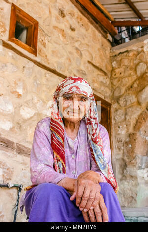 Unidentified vecchio turco donna musulmana pone per la fotocamera nella parte anteriore di una vecchia casa di pietra in Kemaliye,Erzincan,Turchia.Luglio 05 2014. Foto Stock