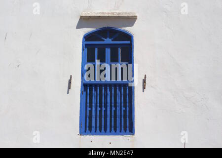 Finestra blu contro un muro bianco a Essaouira, Marocco Foto Stock