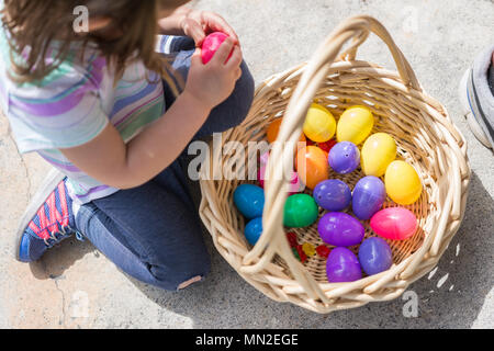 Bambino raccoglie in plastica colorate le uova nel paniere Foto Stock