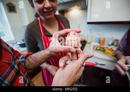 Immagine ravvicinata di un uovo di pollo con una faccia disegnata su di esso nella penna rossa. Foto Stock