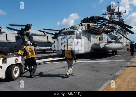 170825-N-NB544-049 CORAL SEA (Agosto 25, 2017) Aviation Boatswain Compagni (manipolazione) utilizzare un come32/A-39 a bordo trattore di traino per spostare un CH-53E Super Stallion, assegnato al 'Dragons' del mezzo marino Tiltrotor Squadron (VMM) 265 (rinforzato), sul ponte di volo dell'assalto anfibio nave USS Bonhomme Richard (LHD 6). Bonhomme Richard, ammiraglia del Bonhomme Richard Expeditionary Strike gruppo, è operativo in Indo-Asia regione del Pacifico per rafforzare le partnership e di essere una pronta risposta in vigore per qualsiasi tipo di emergenza. (U.S. Foto di Marina di Massa lo specialista di comunicazione 2a classe Kyle Carlstr Foto Stock