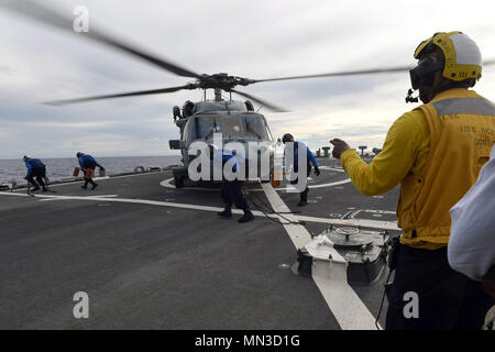 170824-N-RB168-941 PHILLIPINE MARE (feb. 24, 2017) di Boatswain Mate 3° di classe Marcus Stokes, nativo di Chicago, Illinois, dirige come il ponte di volo equipaggio rimuove i gessi e catene da un MH-60 falco di mare sul ponte di volo dell'Arleigh Burke-class guidato-missile destroyer USS Benfold (DDG 65) durante la Pacific Griffin 2017. Pacific Griffin è un esercizio tra Stati Uniti e Repubblica di Singapore navy (RSN), che rappresentano le funzionalità avanzate di entrambe le Marine Militari di operare e lavorare insieme per garantire la sicurezza marittima e la stabilità. (U.S. Foto di Marina di Massa lo specialista di comunicazione di prima classe ben Foto Stock