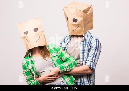 Amore giovane che coprono i loro volti con sacchetto di carta su sfondo bianco Foto Stock