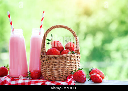 Cocktail di fragole o frullato in un vaso, cesto di fragole su un picnic, cibo sano per la prima colazione e snack. Foto Stock