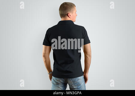 Torna Mockup polo nera su un modello maschile per un esempio di design. Uomo isolato su sfondo grigio. Foto Stock