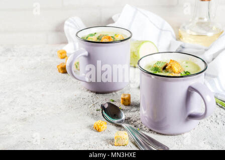 Due porzioni di zucchine fatti in casa zuppa cremosa con briciole di pane in tazze su un calcestruzzo leggero sottofondo. Foto Stock