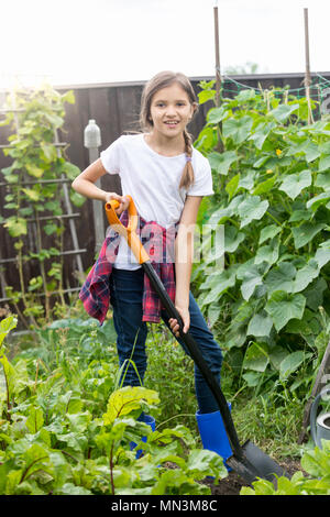 Giovane e bella ragazza del terreno di scavo in giardino con spade Foto Stock