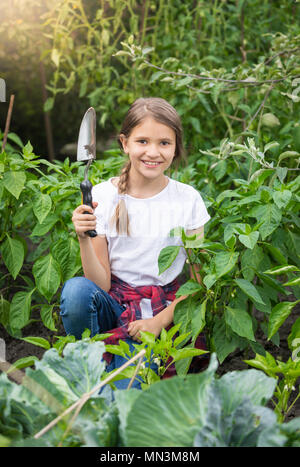 Ritratto di bella ragazza sorridente in posa con frattazzo in giardino Foto Stock