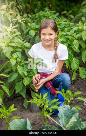 Ritratto di girlspudding bellissimo terreno con cazzuola tra le righe della coltivazione di ortaggi in giardino Foto Stock