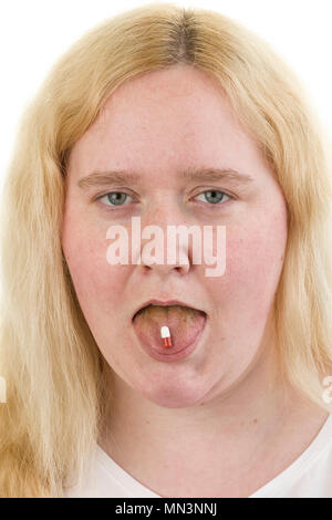 Giovane bionda caucasica donna femmina spuntavano lingua con capsula di medicina su di esso isolato su sfondo bianco modello di rilascio: Sì. Proprietà di rilascio: No. Foto Stock