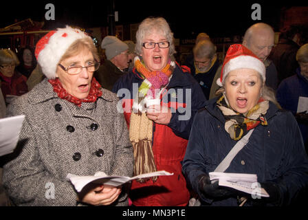 La popolazione locale a cantare i canti natalizi all'aperto in piazza locale, Liphook, Hampshire, Regno Unito. 15.12.2014. Foto Stock