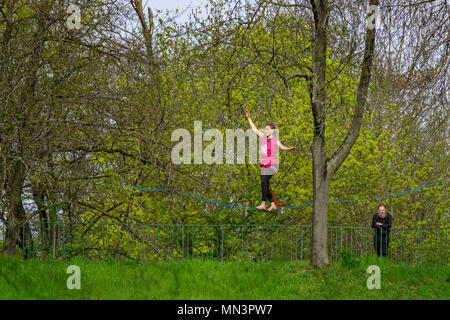 Giovane donna funambolo camminando su un slackline sospesi in aria in un parco, Strasburgo, Francia. Foto Stock