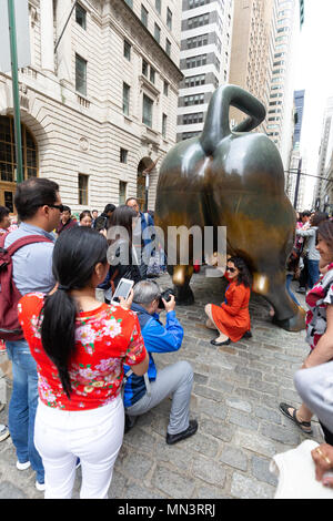 I turisti in posa con la estremità posteriore del Wall Street Bull, il centro cittadino di New York City, Stati Uniti d'America Foto Stock