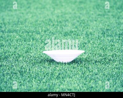 Cono di allenamento per il calcio su un campo verde. Artificiale di tappeto erboso verde dello sfondo. Inverno giochi di calcio con erba in plastica Foto Stock