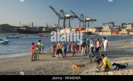 La gente del posto sulla spiaggia con una nave portacontainer lasciando la porta al di là di Santa Marta, Magdalena, Colombia Foto Stock