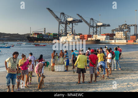 La gente del posto sulla spiaggia con una nave portacontainer lasciando la porta al di là di Santa Marta, Magdalena, Colombia Foto Stock