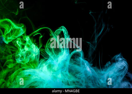 Denso fumo multicolore di colori blu e verde su un isolato bianco sullo sfondo. Sfondo di vape fumo Foto Stock
