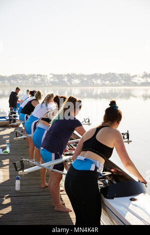 I rematori femmina scull abbassamento da lakeside dock Foto Stock