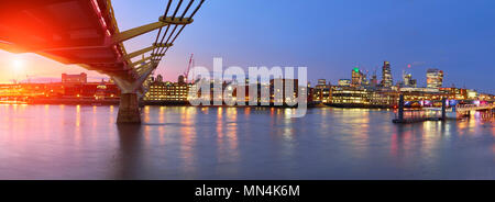 Londra al tramonto, Millennium bridge che conduce verso illuminato San Paolo cattedrale oltre il Tamigi con la città di balneazione in luce elettrica. Per panoramiche Foto Stock