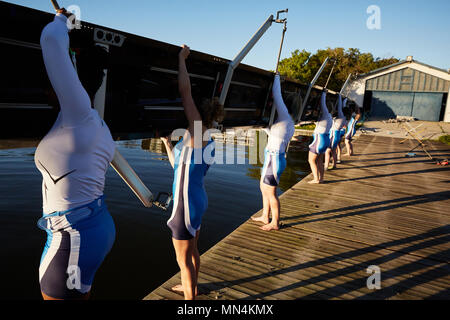 I rematori femmina scull sollevamento di sunny lakeside dock Foto Stock