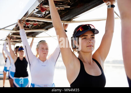 Fiducioso, determinata femmina team di canottaggio di sollevamento overhead scull Foto Stock