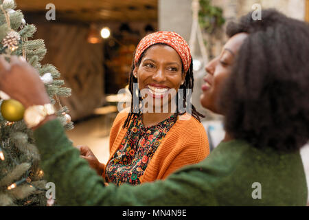 Sorridente madre e figlia decorare albero di Natale Foto Stock