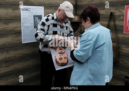 I civili hanno in mano un poster con la foto di Stalin mentre hanno allestito uno stand commemorativo durante il giorno della Vittoria il 9 maggio, una festa che commemora la vittoria dell'Unione Sovietica sulla Germania nazista nel 1945 nella città di Bender de facto nome ufficiale Bendery all'interno del mondo confini riconosciuti della Moldavia sotto il controllo de facto della Repubblica moldava di Pridnestrovia, chiamata anche Transnistria (PMR), non riconosciuta dal 1992. Foto Stock