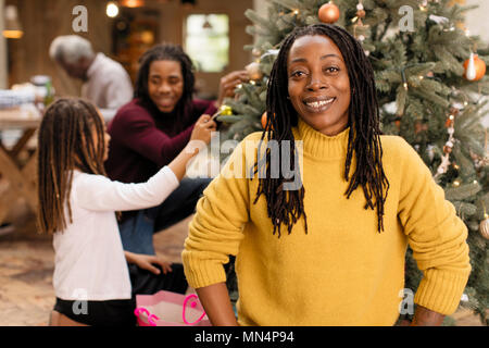 Ritratto di donna sorridente decorare albero di Natale con la famiglia Foto Stock