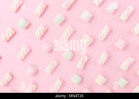 Diversi colori pastello marshmallows in rosa pastello con sfondo spazio copia. Vista dall'alto. Concettuale Trend alimentari laici piatta Foto Stock
