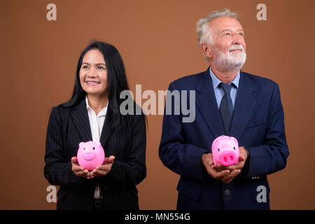 Coppia multi-etnico azienda giovane contro sfondo marrone Foto Stock
