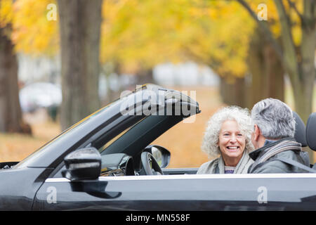 Sorridente coppia senior parlando nel convertibile Foto Stock