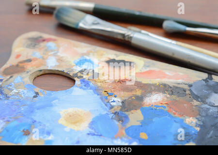 Artista della tavolozza con colorati olio pennellate di vernice e pennelli su sfondo di legno. Il concetto di arte Foto Stock