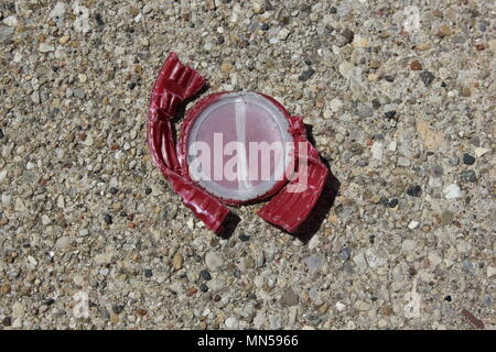 Smushed e appiattite red tappo di bottiglia trovati sul terreno di un parcheggio in Chicago suburbana. Foto Stock