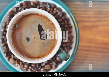Una tazza di caffè nero su un piattino con i chicchi di caffè. Foto Stock