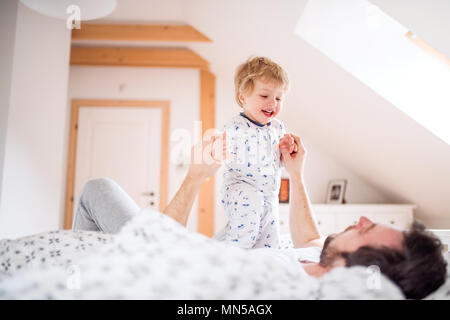 Padre maturo con un bimbo piccolo ragazzo divertendosi in camera da letto a casa prima di andare a dormire. Congedo di paternità. Foto Stock