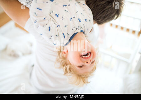 Irriconoscibile padre tenendo un felice toddler boy capovolto. Congedo di paternità. Foto Stock