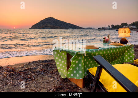 Cena romantica impostazione sulla spiaggia al tramonto a Bodrum, Gumusluk, Turchia. Foto Stock