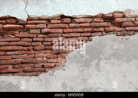 Sullo sfondo di un vecchio muro di mattoni rotti. Foto Stock