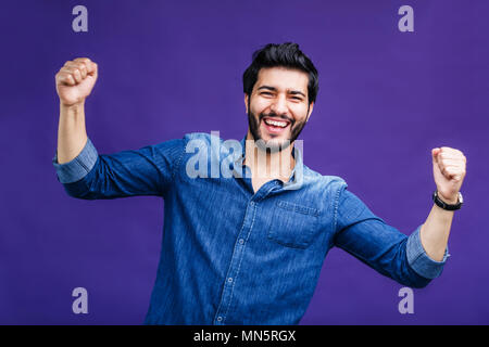 Ritratto di felice successo uomo vestito in denim shirt su sfondo viola Foto Stock