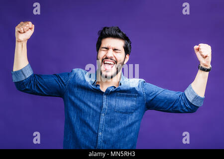 Ritratto di felice successo uomo vestito in denim shirt su sfondo viola Foto Stock