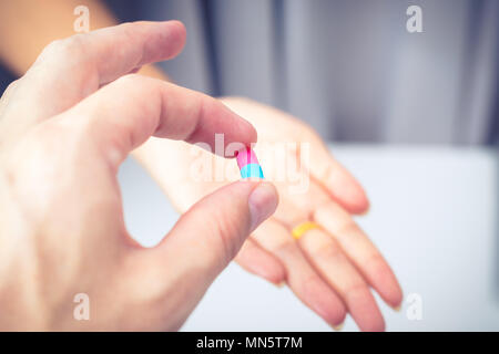 La mano di un medico dando una pillola di farmaco per il suo paziente Foto Stock