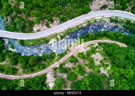 Vista aerea del drone su strada di montagna e le curve andando attraverso il paesaggio forestale Foto Stock