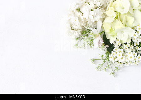 Elegante stock photo. Decorativi composizione floreale. Wild matrimonio o compleanno bouquet di fioritura lilla bianco, apple il ramo di un albero hydrangea, spirea fiori. Tavolo bianco sullo sfondo. Lay piatto Foto Stock