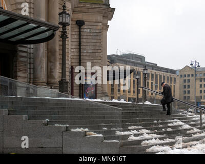 Un anziano uomo cammina su strade coperte di neve passi verso la Usher Hal, Edimburgo, Scozia Foto Stock